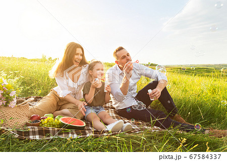 Cute family of three playing together on a picnic Cute family of three playing together on a picnic 67584337