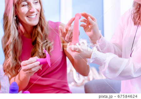 Woman asking saleslady for details of dildo on adult toy party 67584624