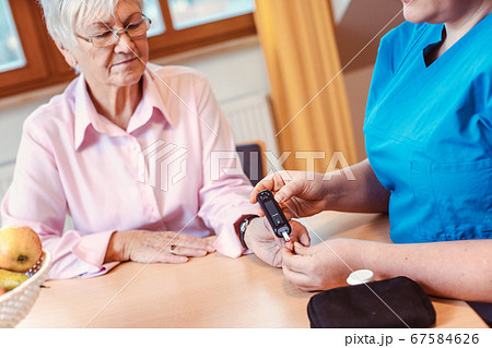 Nurse administers diabetes test to senior in nursing home Nurse administers diabetes test to senior in nursing home 67584626