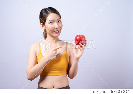 Asian woman in sportswear holding an apple isolated on white background Asian woman in sportswear holding an apple isolated on white background 67585034