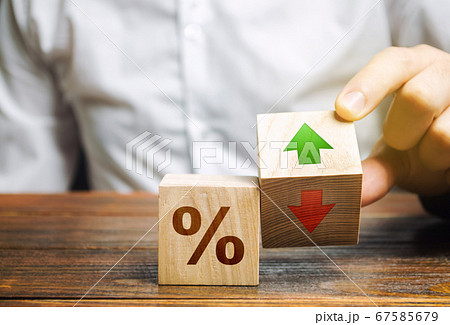 Businessman holds wooden blocks with percent and up or down arrow. Mortgage and loan rates. Interest rate, stocks, ranking. Business and finance concept. Businessman holds wooden blocks with percent and up or down arrow. Mortgage and loan rates. Interest rate, stocks, ranking. Business and finance concept. 67585679