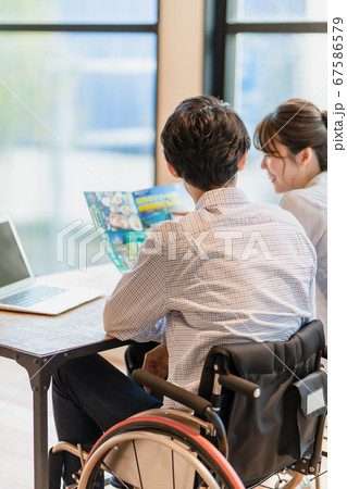旅行のパンフレットを見ながら計画を立てる男女 67586579