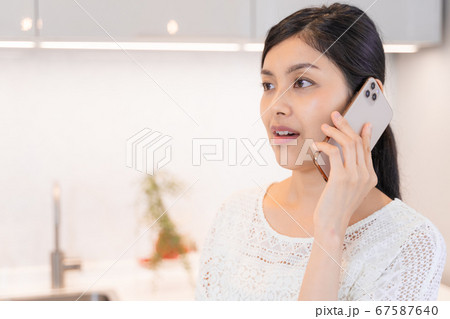 ダイニング・キッチンにてスマホで電話する若い女性 ダイニング・キッチンにてスマホで電話する若い女性 67587640