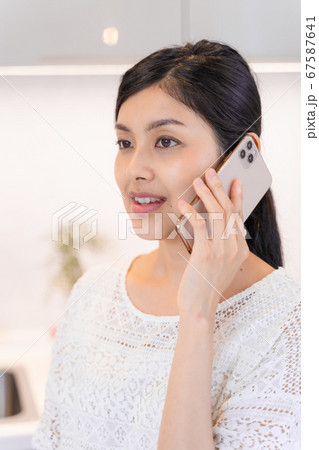 ダイニング・キッチンにてスマホで電話する若い女性 ダイニング・キッチンにてスマホで電話する若い女性 67587641