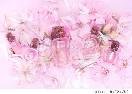 Essential oil bottles on pink clover flowers and medicinal herbs background, shallow DOF, toned	 67587764