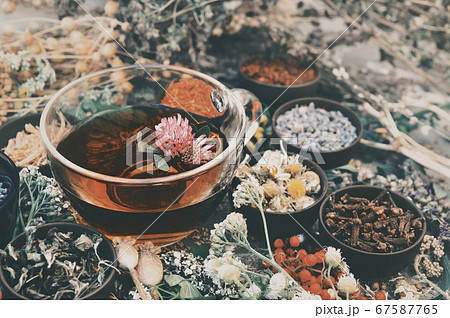 Toned image of healthy herbal tea on medicinal flowers and herbs background, selective focus 67587765