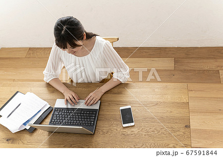資料を見てノートパソコンの操作をする若い女性 資料を見てノートパソコンの操作をする若い女性 67591844