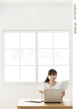 在宅勤務でスマホで報告連絡相談する若い女性 67591955