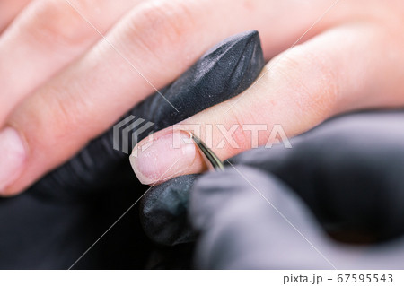 Process manicure close-up. Preparation for hardware manicure. Beautician in rubber gloves cuts the cuticle and processes nails. 67595543