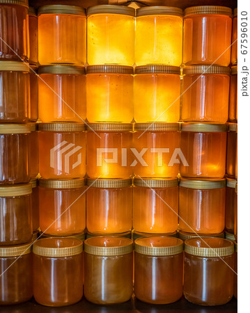 Tower and rows of Golden yellow honey in glass jar on wooden board Closeup Copy space 67596010
