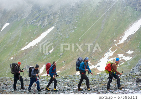 Group of travelers hiking in mountains in Austria. Group of travelers hiking in mountains in Austria. 67596311