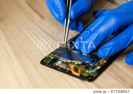 Technician repairing mobile phone at table, 67598607