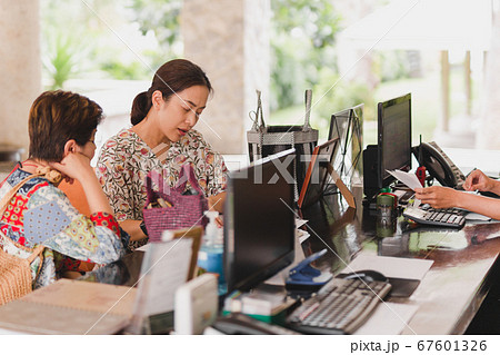 Two female guest checking hotel documents at reception. 67601326