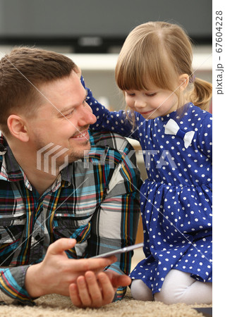 Cute little girl on floor carpet with dad and smartphone 67604228