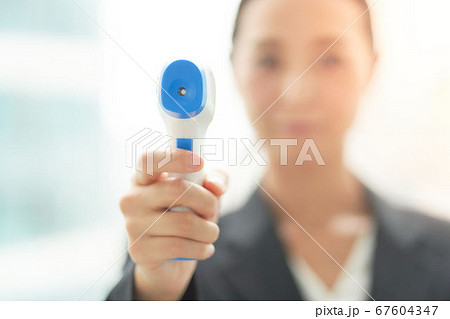 非接触温度計で検温をする女性 67604347