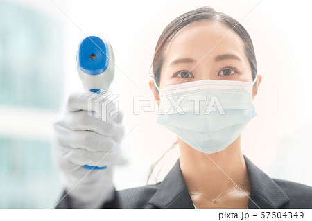 非接触体温計で検温をする女性 非接触体温計で検温をする女性 67604349