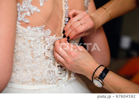 bridesmaid hands fastens buttons on the back of the bride bridesmaid hands fastens buttons on the back of the bride 67604592