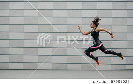 Excellent training running. African american girl in sportswear froze in air above ground, jumping Excellent training running. African american girl in sportswear froze in air above ground, jumping 67605022