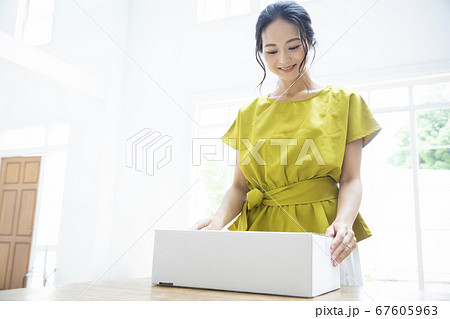 段ボール箱を開ける笑顔の女性 67605963