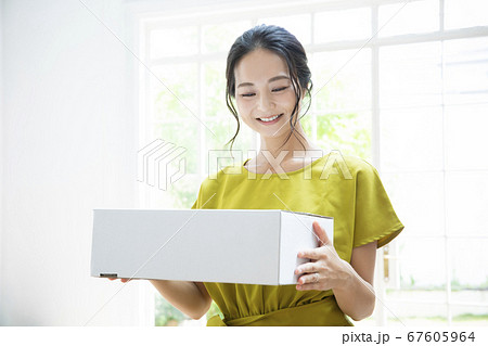 段ボール箱を持つ笑顔の女性 67605964