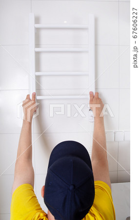 Renovation in the bathroom. A plumber installs a heated towel rail.  67606227