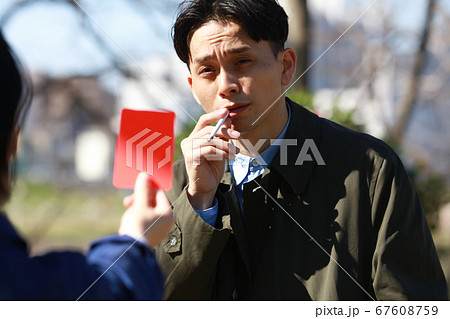 レッドカードを出される歩きタバコの男性の写真素材