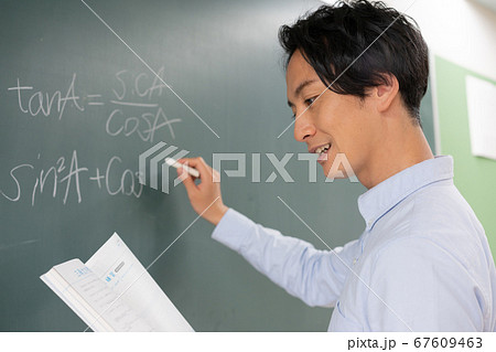 黒板に数式を書く若い男性教師 67609463