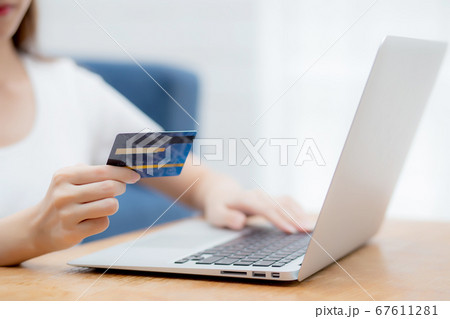 Hand of young woman holding credit card buying shopping online with laptop computer. 67611281