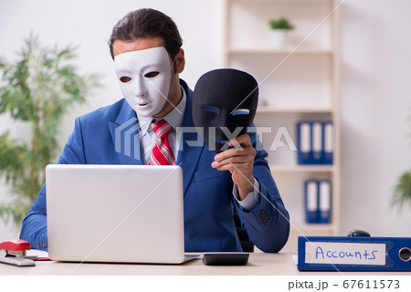 Male employee with mask in hipocrisy concept Male employee with mask in hipocrisy concept 67611573