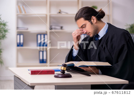 Young male judge working in courthouse 67611812