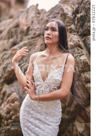 Beautiful asian woman posing on a beach with rocks 67612225