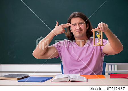 Young male student in the classroom at time management concept Young male student in the classroom at time management concept 67612427