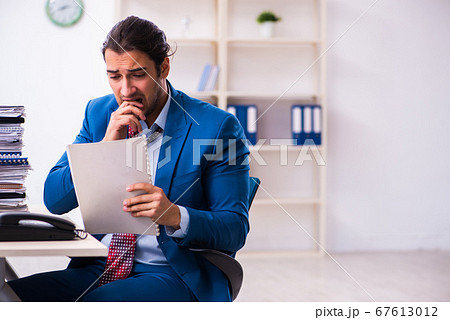 Young male employee unhappy with excessive work Young male employee unhappy with excessive work 67613012