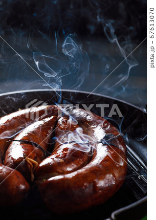 Homemade sausage cooked on a grill, with tomatoes. 67613070