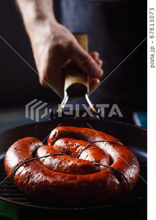 Homemade sausage cooked on a grill, with tomatoes. 67613073