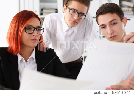 Three young managers discussing documents in office Three young managers discussing documents in office 67613074