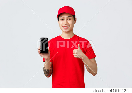 Delivery application, online shopping and shipping concept. Handsome asian courier in red t-shirt and cap, show thumb-up in approval and mobile phone screen app, provide fast and quality service Delivery application, online shopping and shipping concept. Handsome asian courier in red t-shirt and cap, show thumb-up in approval and mobile phone screen app, provide fast and quality service 67614124