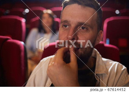 Bearded Man Eating Popcorn in Cinema 67614452