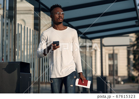 Young handsome Caucasian man in hat with backpack talking with smile on cellphone. Smiling cheerfully at train station. Attractive male traveller speaking on mobile phone at bus stop. Telephone call. Young handsome Caucasian man in hat with backpack talking with smile on cellphone. Smiling cheerfully at train station. Attractive male traveller speaking on mobile phone at bus stop. Telephone call. 67615323