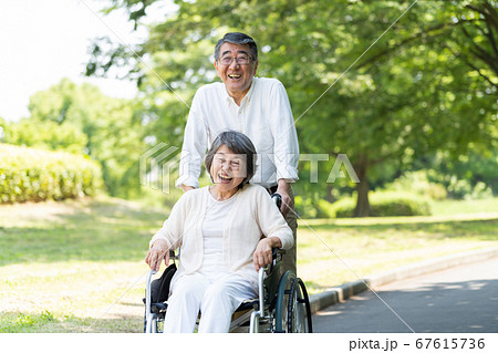車椅子で公園を散歩するシニアのカップル 車椅子で公園を散歩するシニアのカップル 67615736