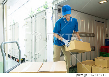 トラックに荷物を積みこむセールスドライバーの女性 67616710