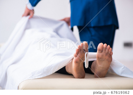 Police coroner examining dead body corpse in morgue 67619362
