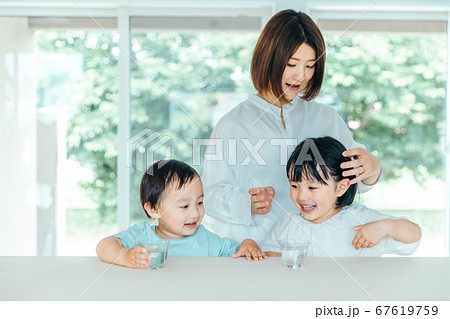 爽やかな白いリビングで楽しそうに水を飲む子どもと母親　kids water family 67619759