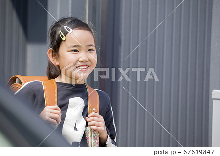 ランドセルを背負って家を出る小学生女の子 登校イメージの写真素材