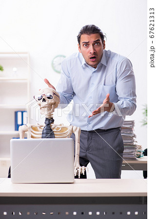 Young male employee and skeleton in the office 67621313