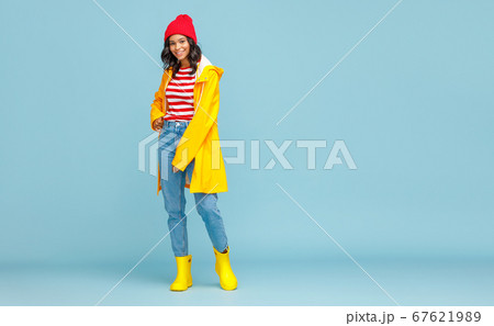 Happy ethnic woman in a yellow raincoat smiling on 67621989