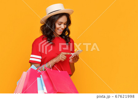 Cheerful female shopaholic using smartphone. 67621998