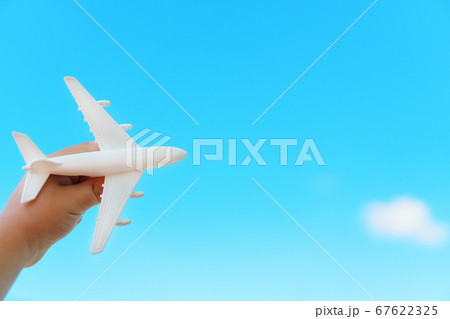 A white airplane in a child's hand against a blue A white airplane in a child's hand against a blue 67622325