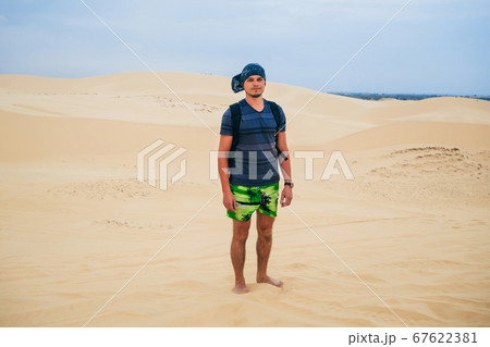 man tourist with a backpack and a bandana in the sandy desert man tourist with a backpack and a bandana in the sandy desert 67622381