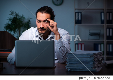Young male employee working in the office night time 67622728
